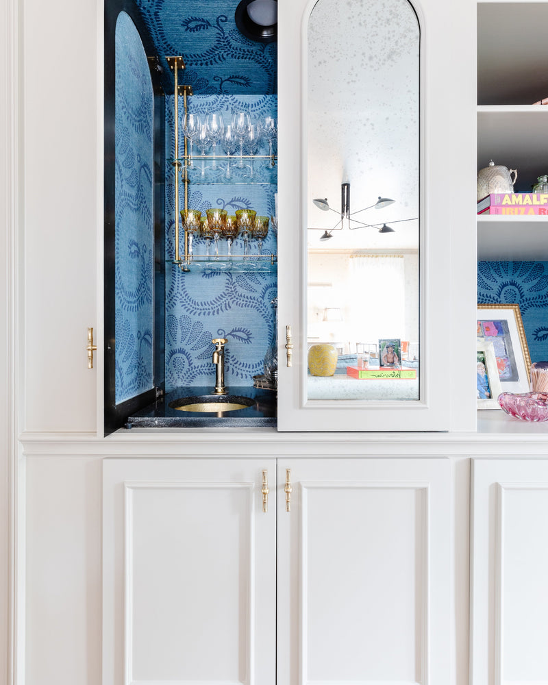 White cabinet with blue wallpapered interior featuring a sink and mirror.